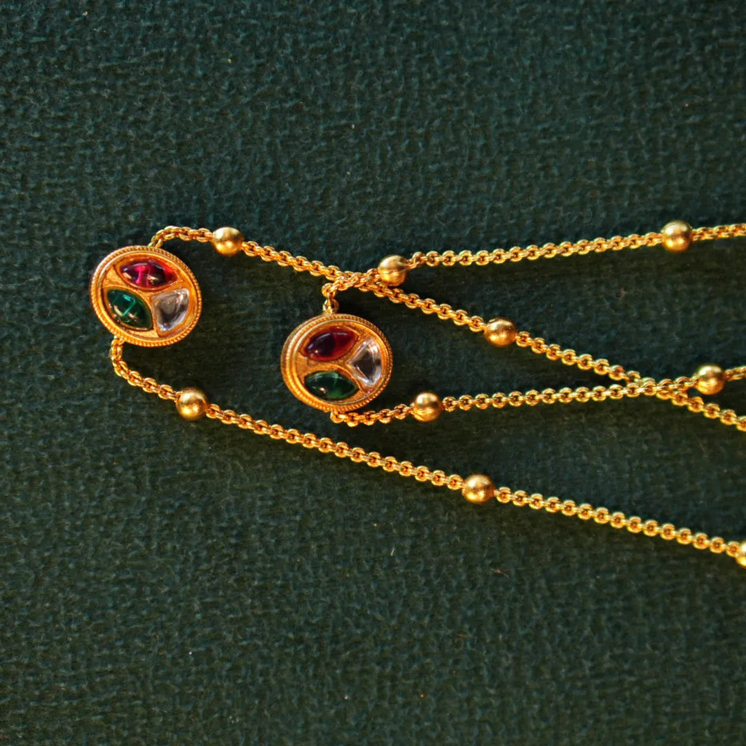 Gold necklace with colorful gemstones on a green textured background