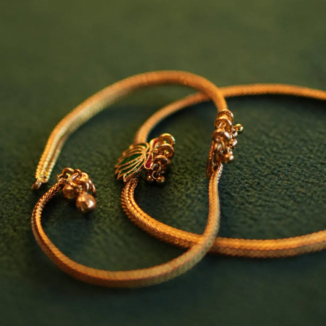 Gold bracelet with decorative elements on a green textured surface