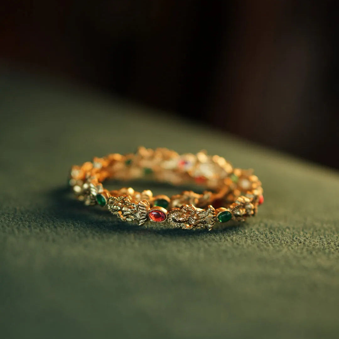 Gold bracelet with colorful stones on a green surface