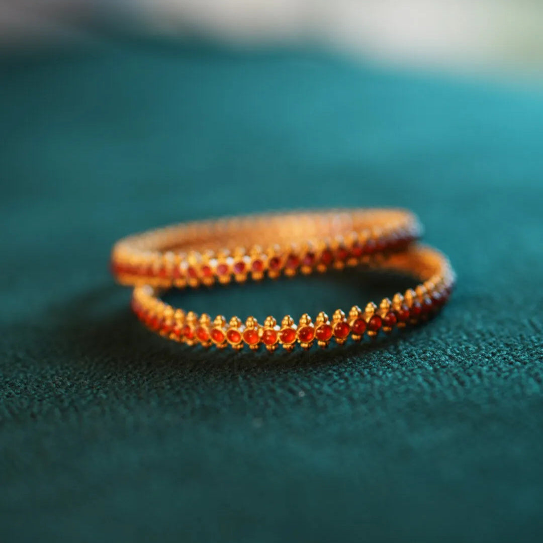 Two orange beaded bracelets on a green surface