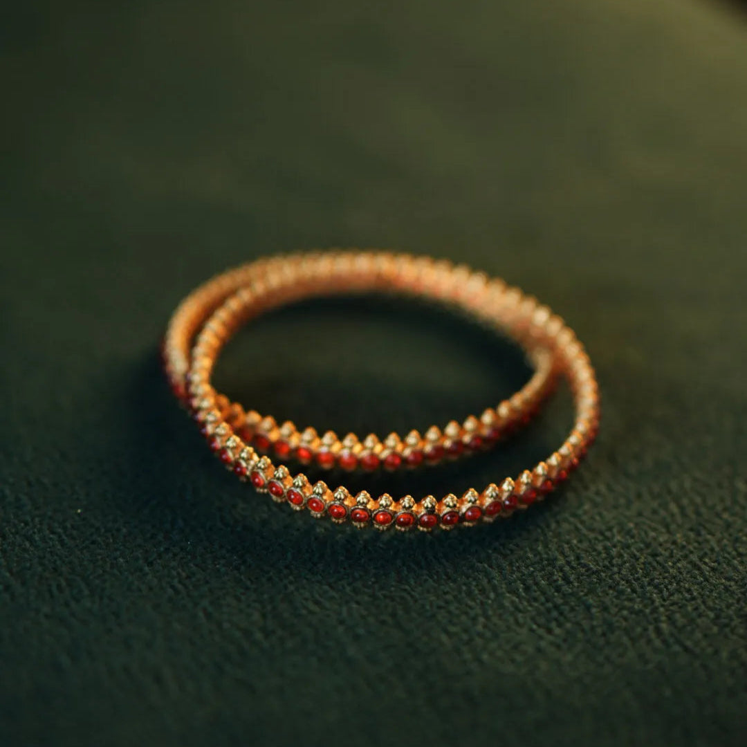 Two beaded bracelets on a dark green surface