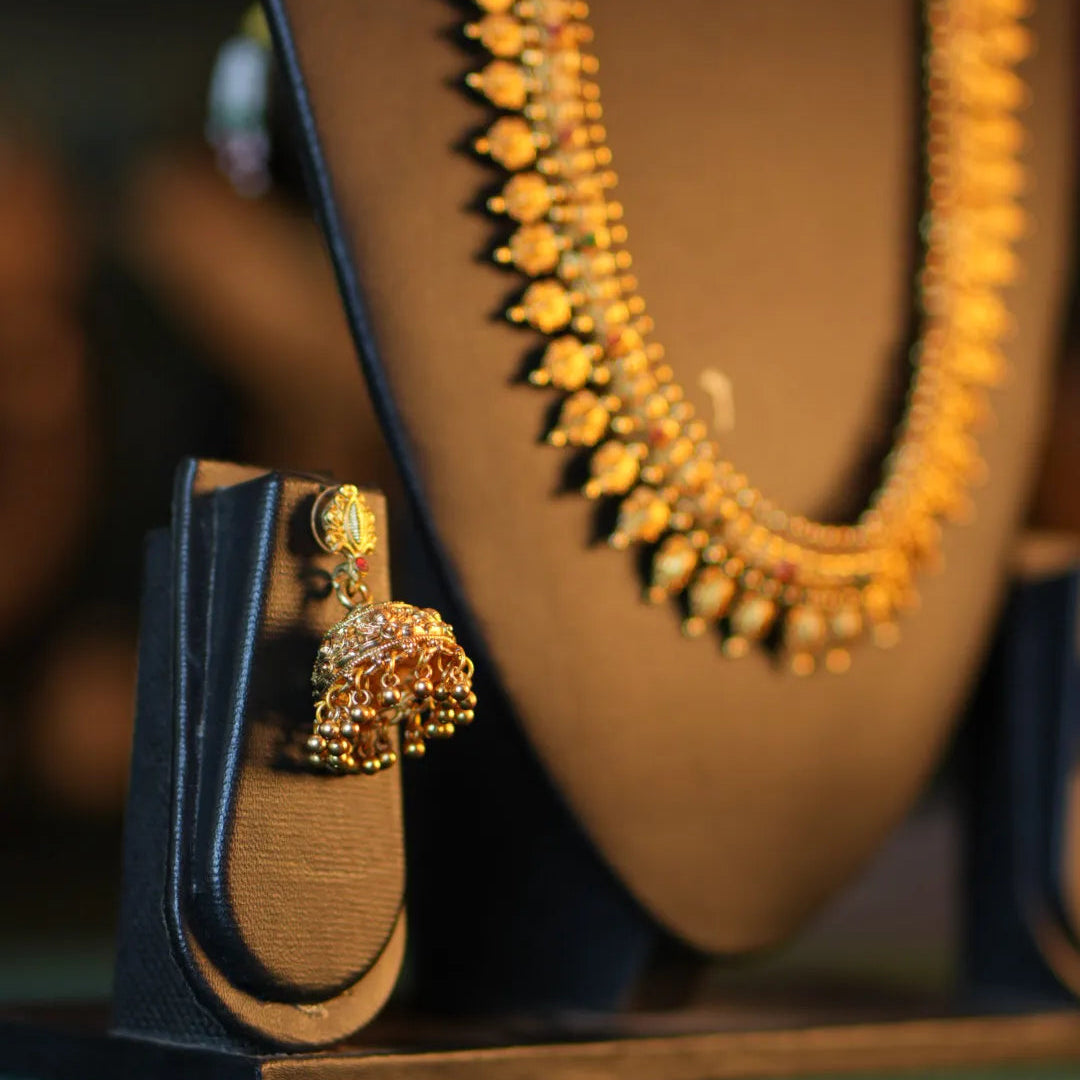 Gold necklace and earrings on a stand with a blurred background