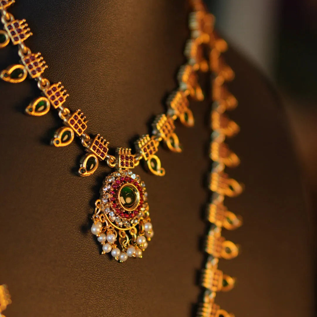Gold necklace with a detailed pendant on a mannequin