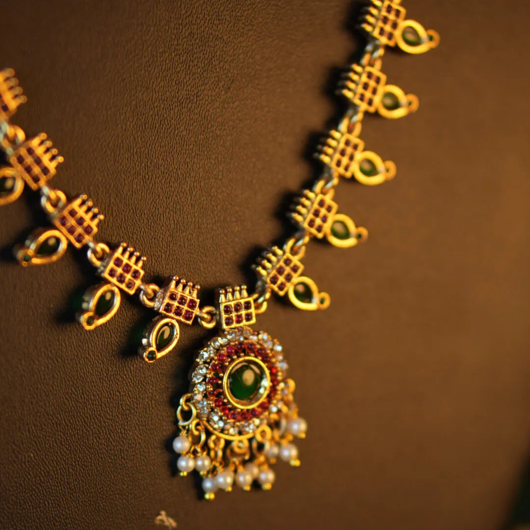 Gold necklace with green gemstone pendant on a brown background
