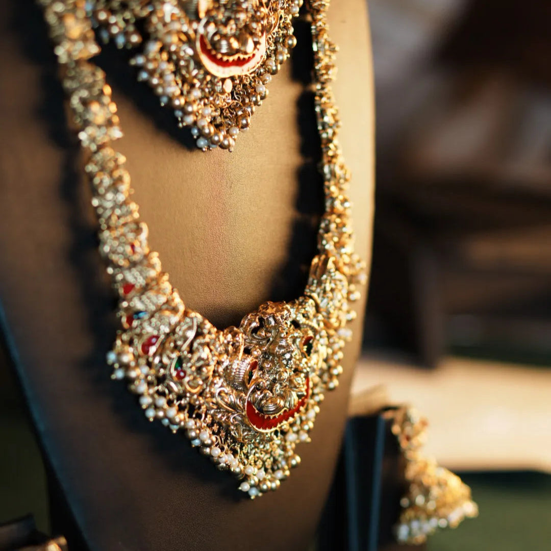 Gold necklace and earrings on a mannequin bust with a blurred background