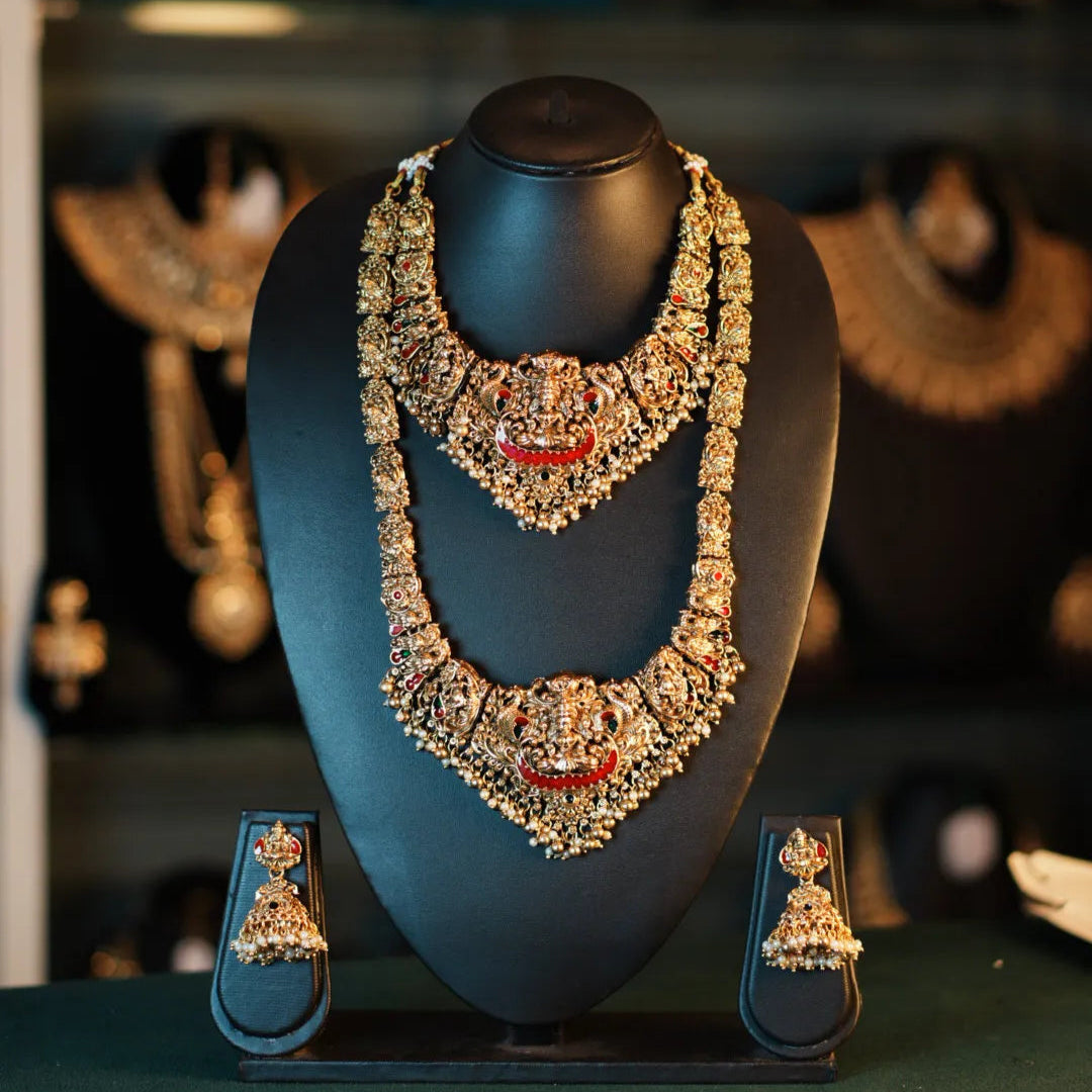 Ornate necklace and earrings on a mannequin bust with a blurred jewelry store background.
