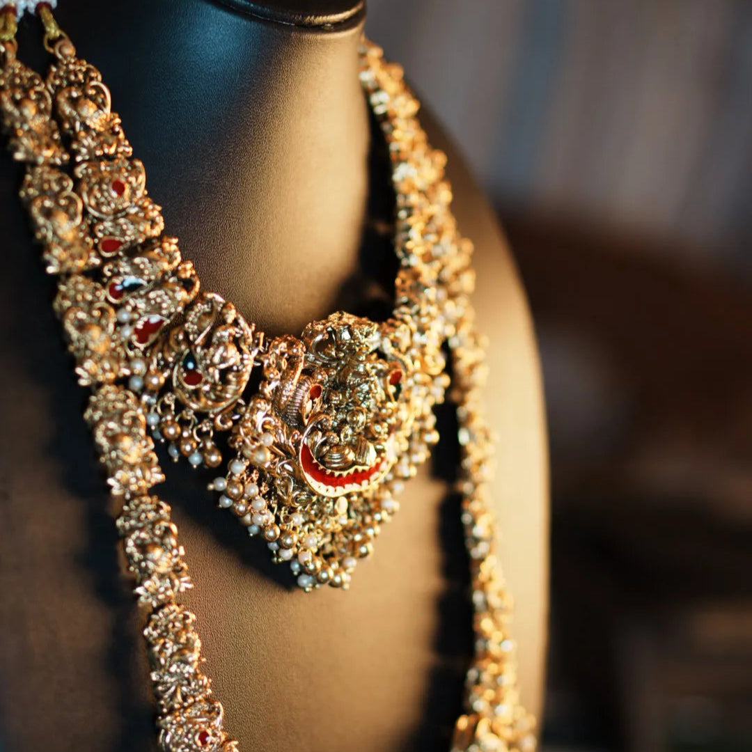 Ornate necklace with heart-shaped pendant on a mannequin bust.