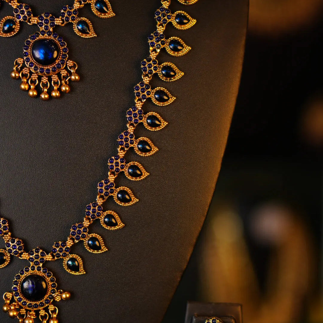 Gold and blue jewelry set on a mannequin with a blurred background