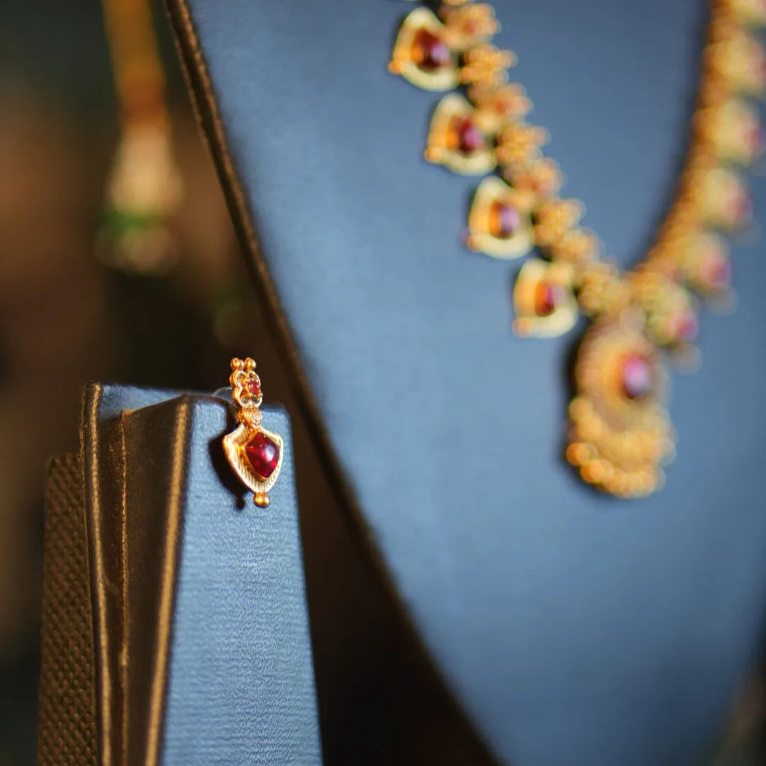 Gold necklace with a heart pendant on a dark blue stand