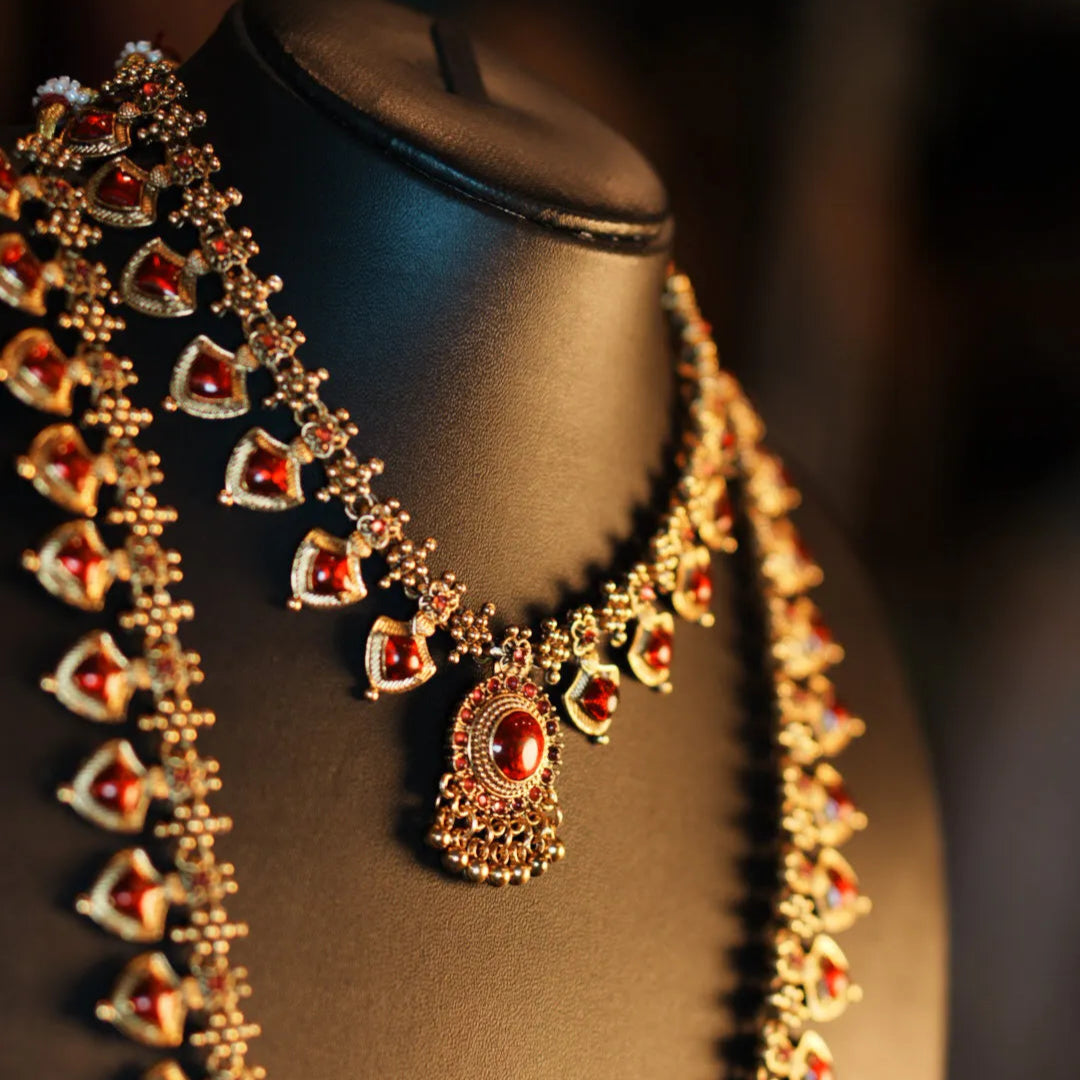 Ornate necklace with red stones on a black mannequin