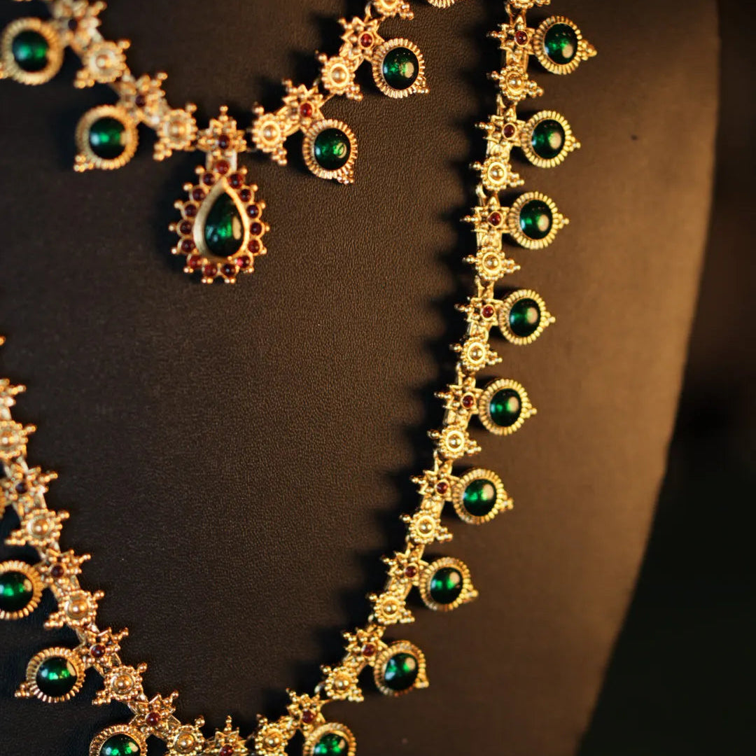 Gold necklace with green gemstones on a black mannequin