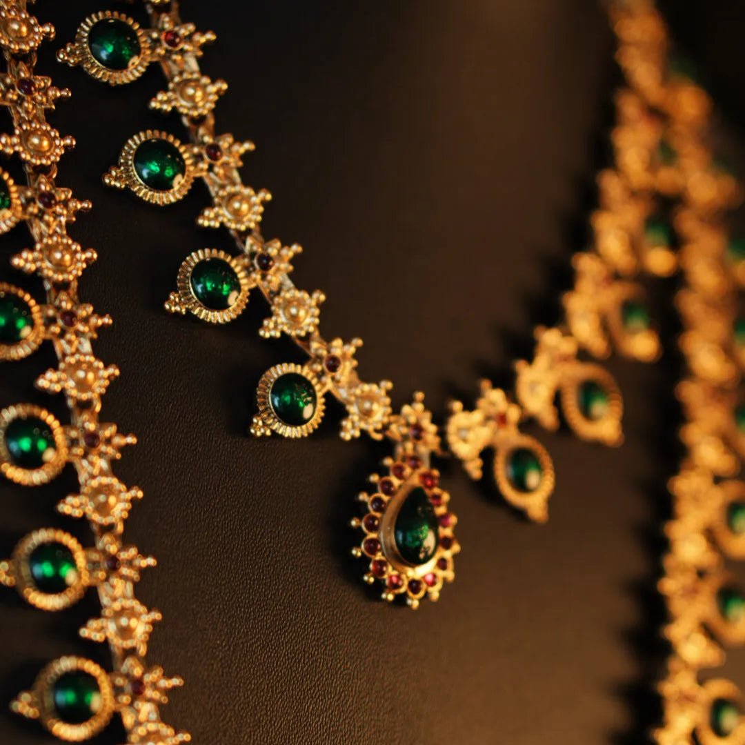 Gold necklace with green gemstones on a dark background