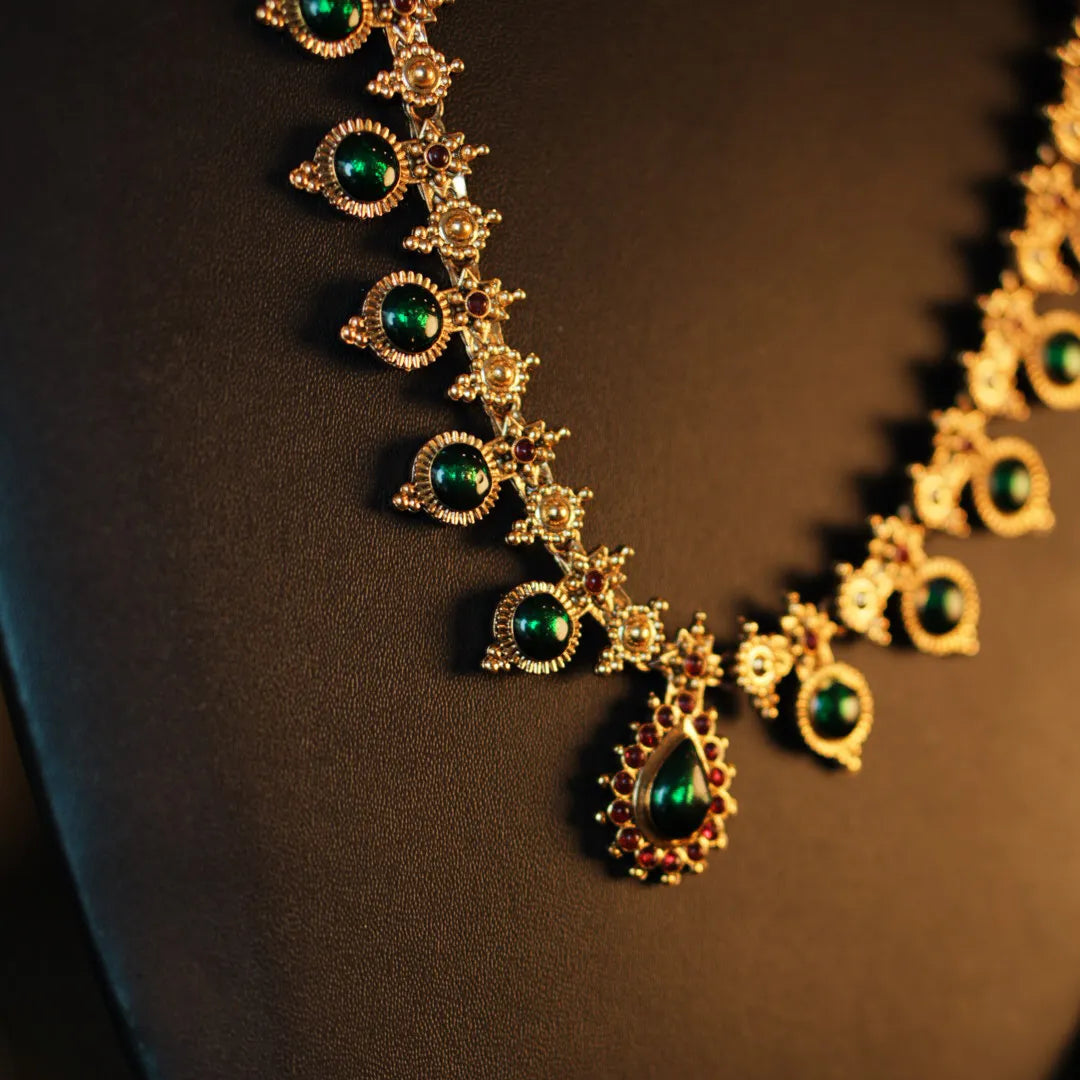 Gold necklace with green gemstones on a dark background