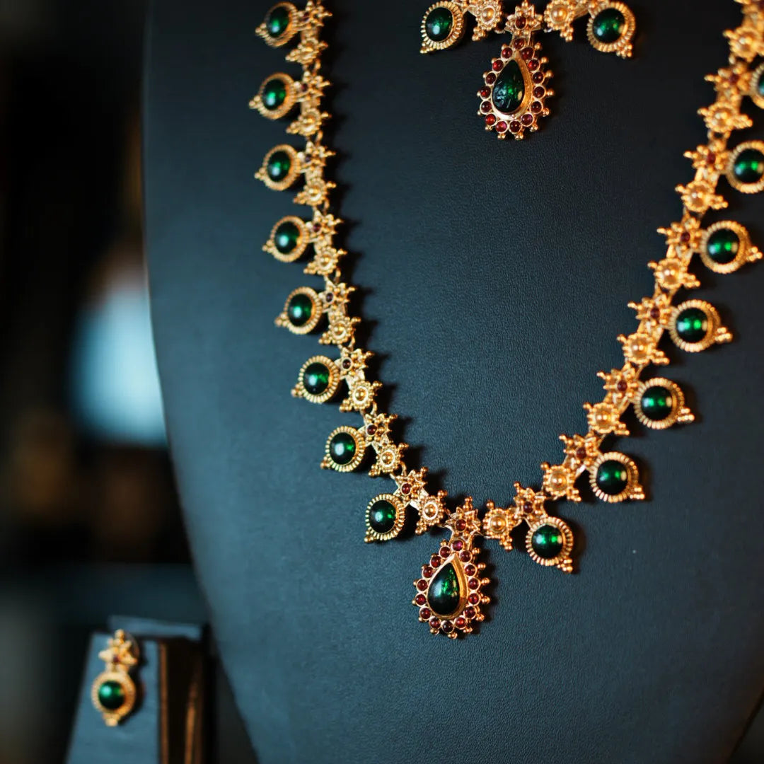 Gold necklace with green gemstones on a dark background