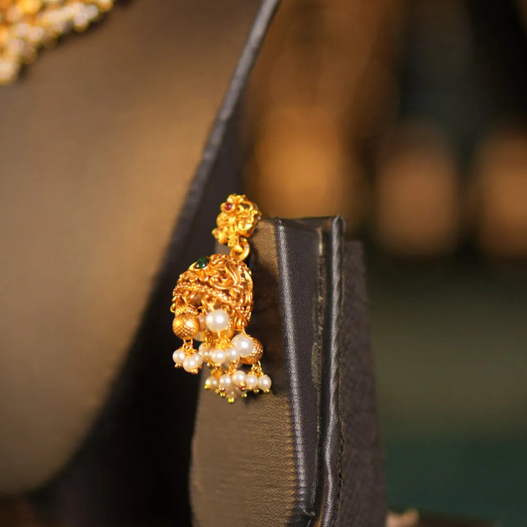 Gold earring on a black stand with a blurred background