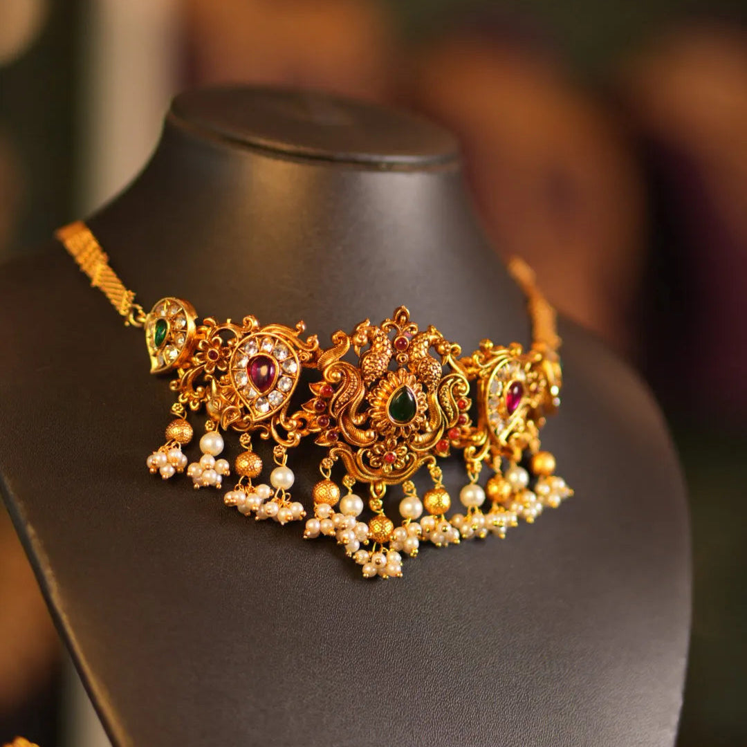 Gold necklace with pearls and gemstones on a mannequin bust.
