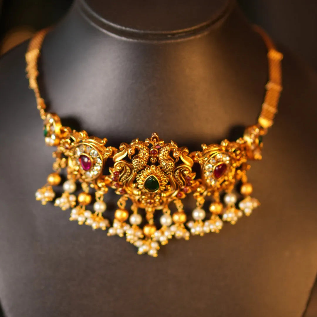 Gold necklace with pearls and gemstones on a black mannequin bust