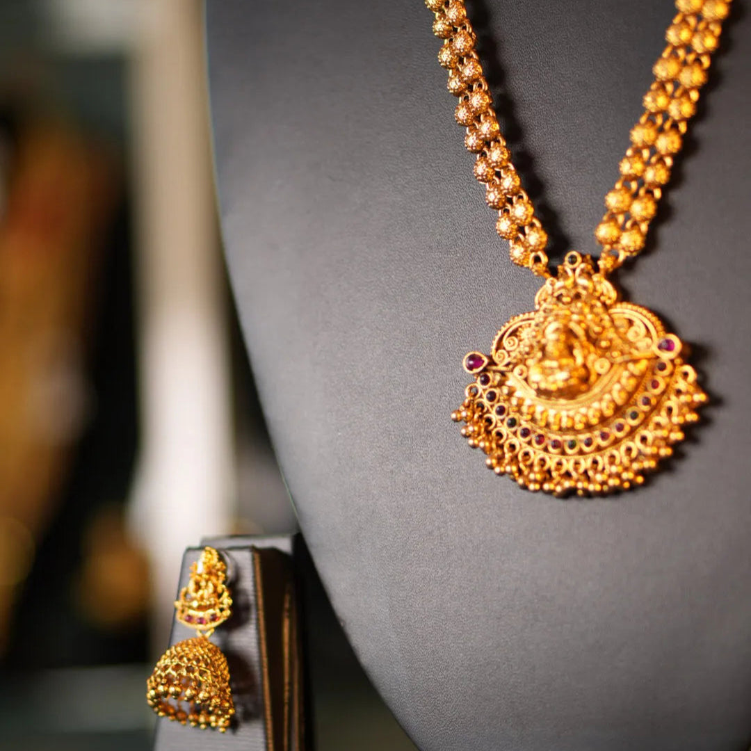 Gold necklace and earrings on a gray mannequin bust