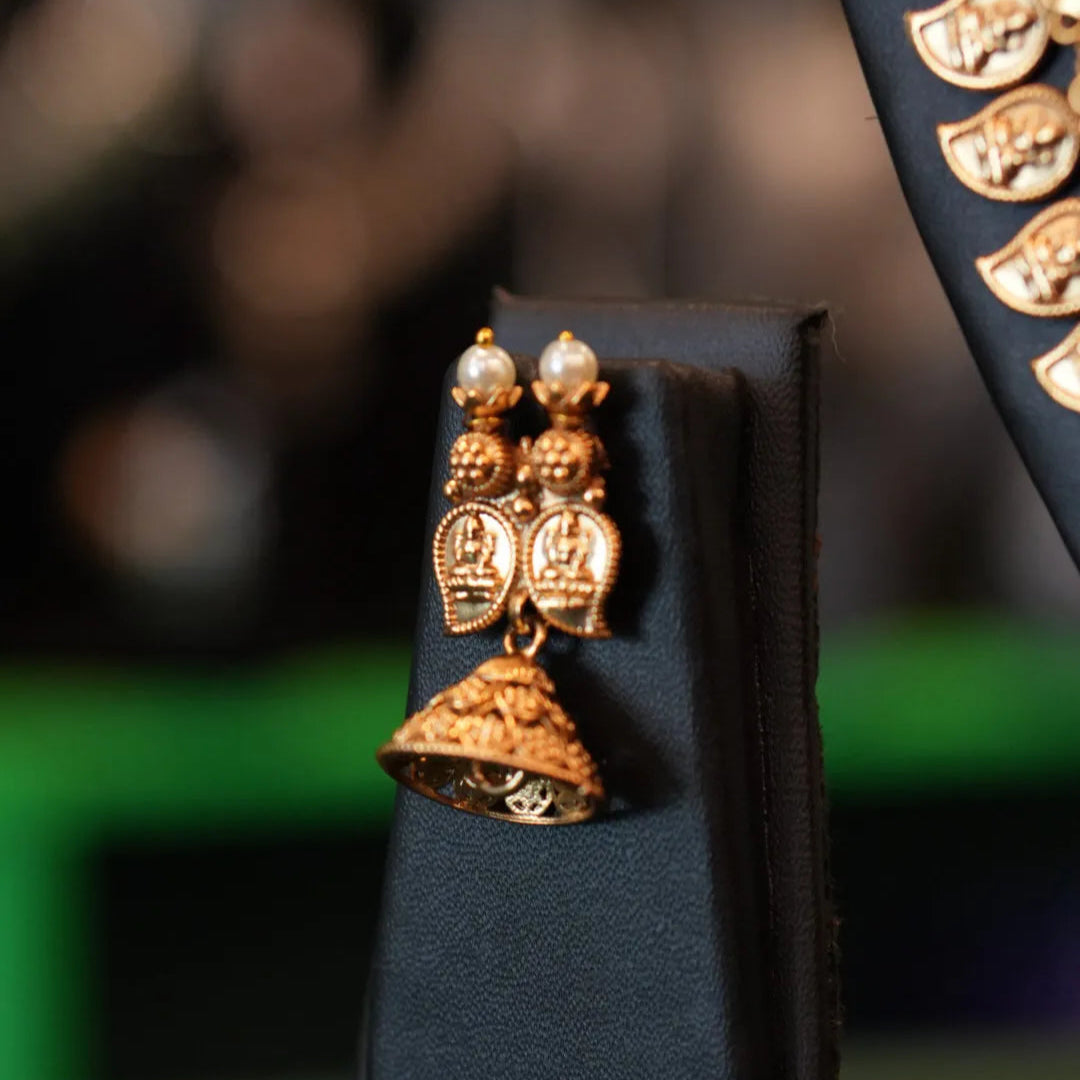 Gold earrings on a black stand with a blurred background