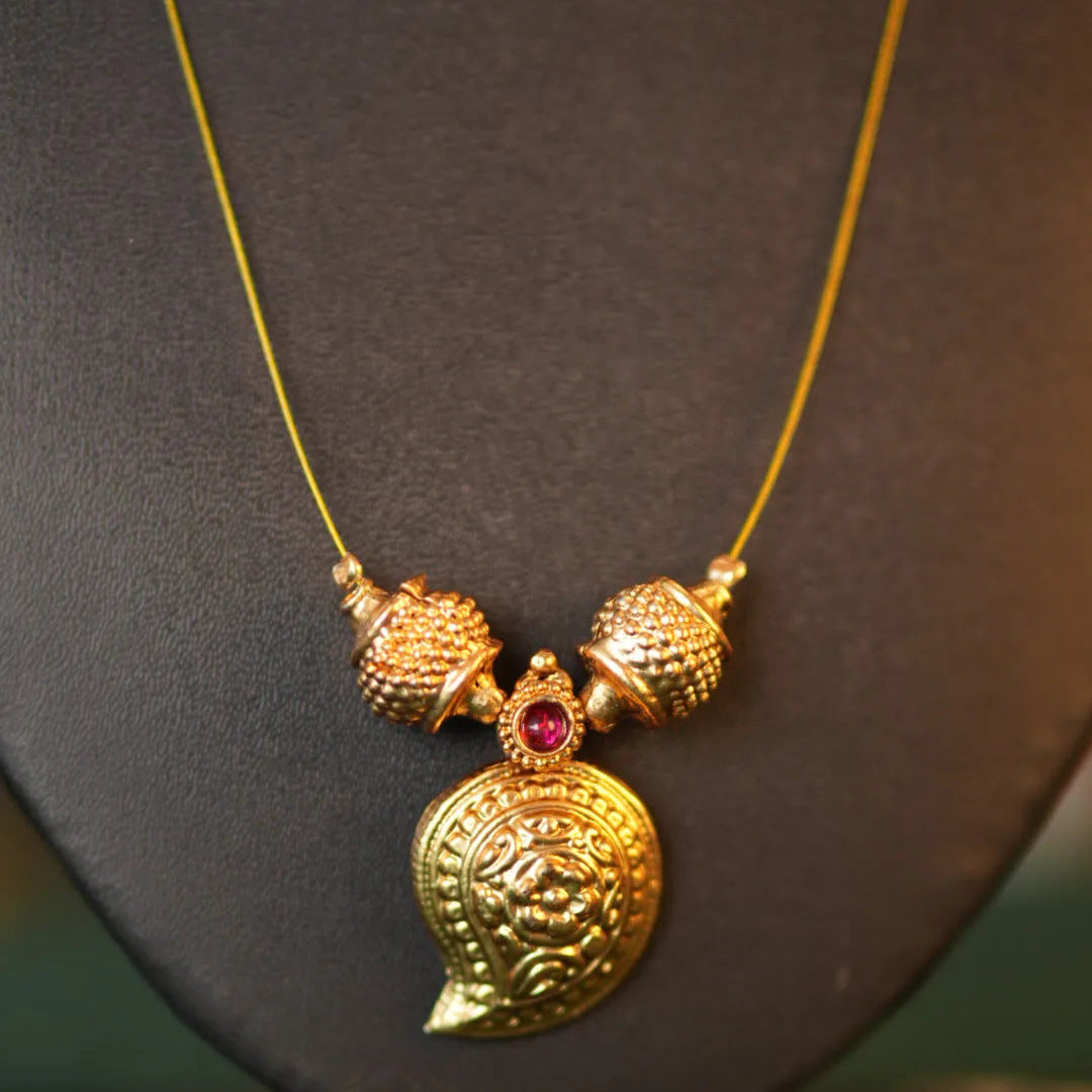 Gold necklace with a detailed pendant on a black stand