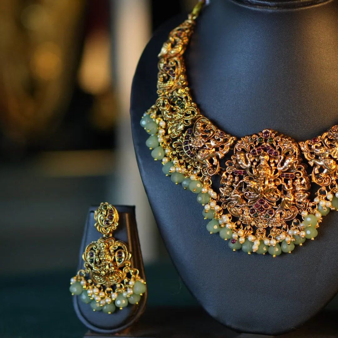 Decorative jewelry piece with gold and green elements on a dark background