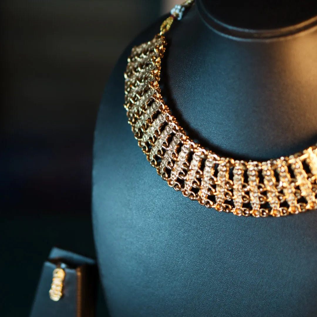 Gold necklace on a black mannequin bust with a blurred background
