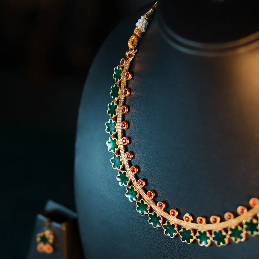 Necklace with green and gold beads on a black mannequin