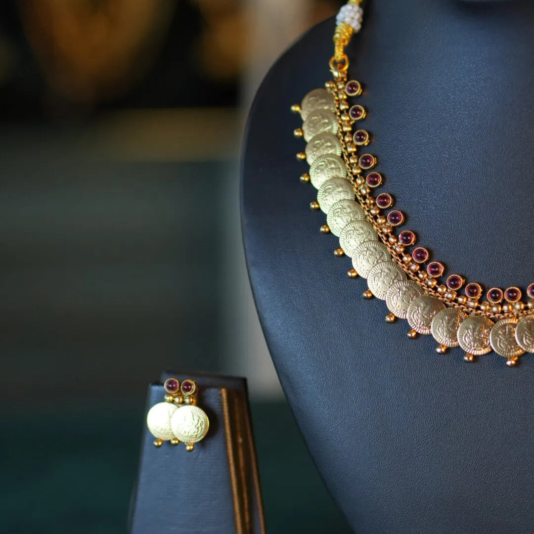 Necklace and earring set on a dark stand with a blurred background