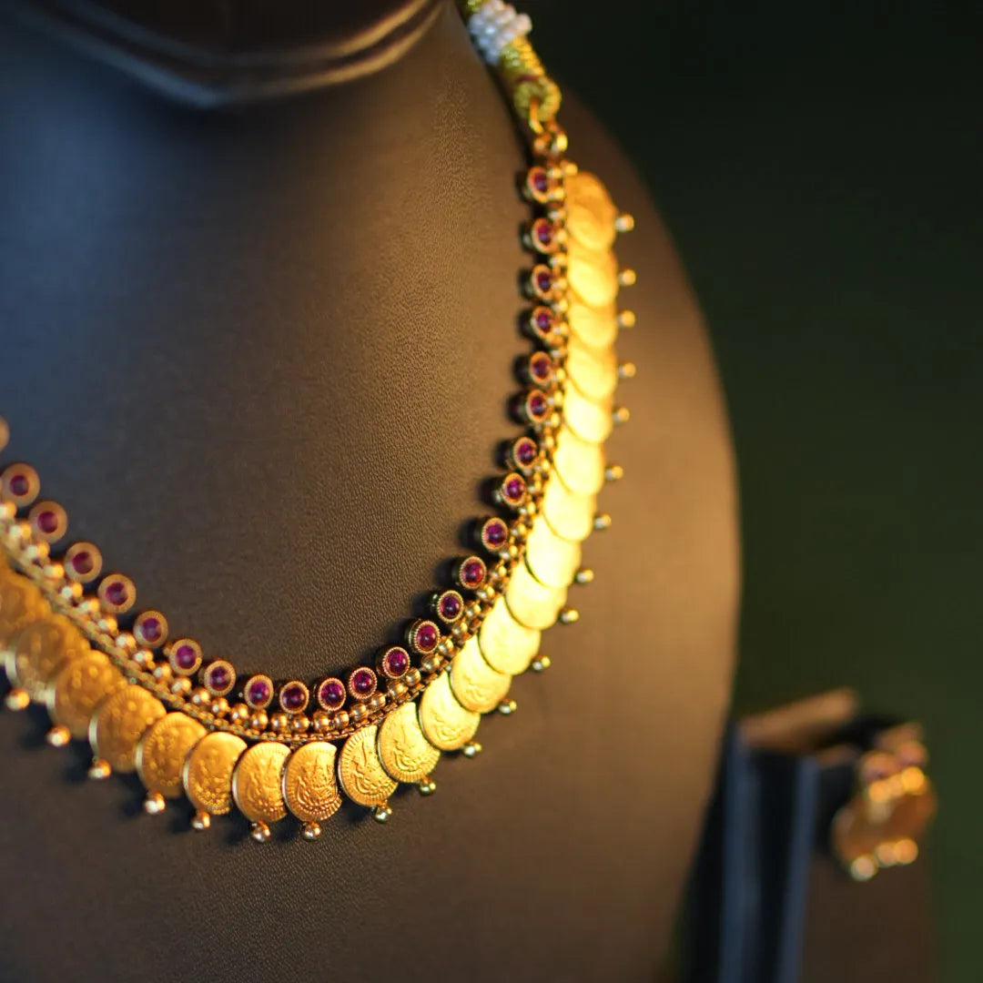 Gold necklace with colorful stones on a black mannequin against a dark background
