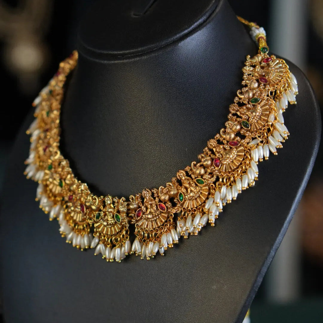 Ornate gold necklace with pearls on a black mannequin