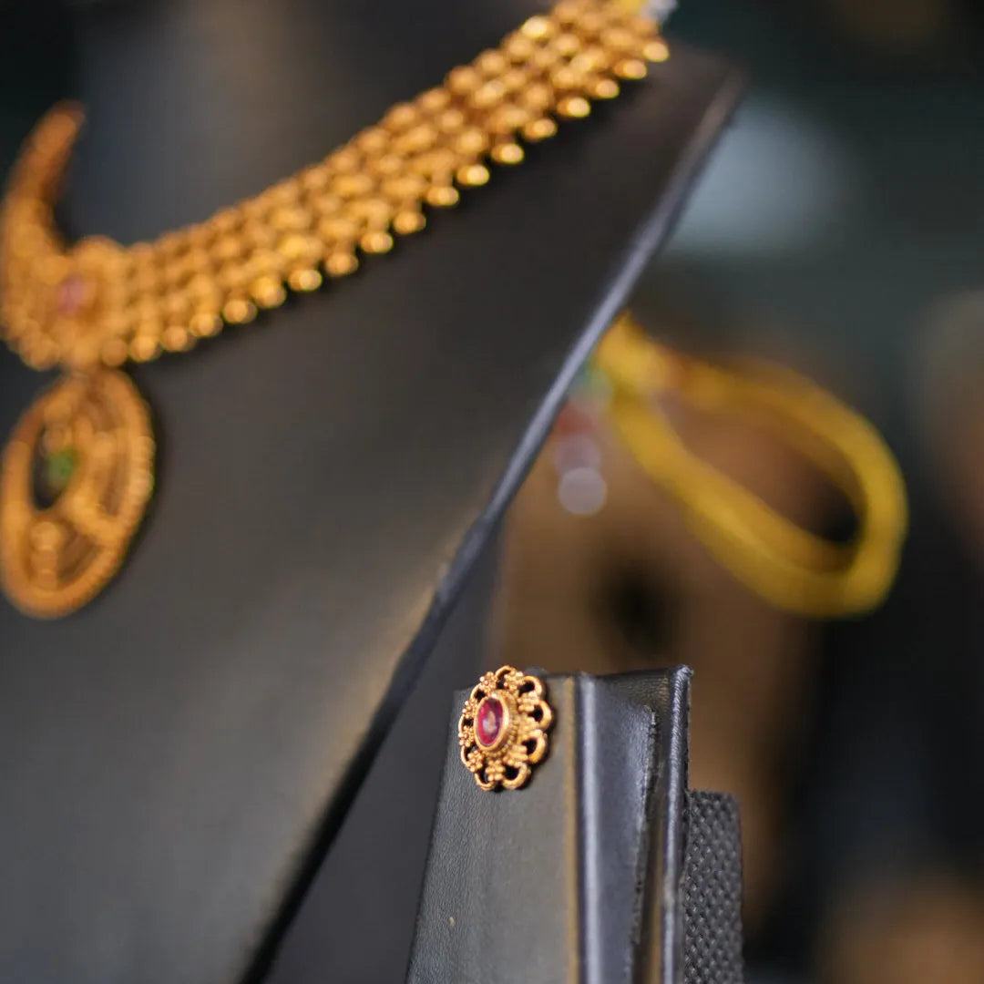 Gold necklace and earring set on a black stand with a blurred background
