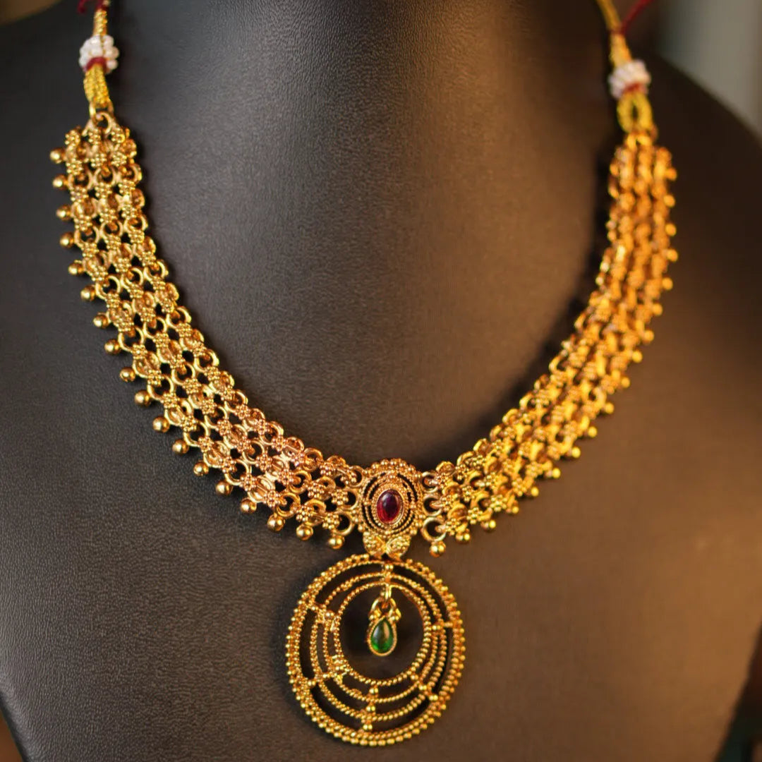 Gold necklace with intricate design on a mannequin