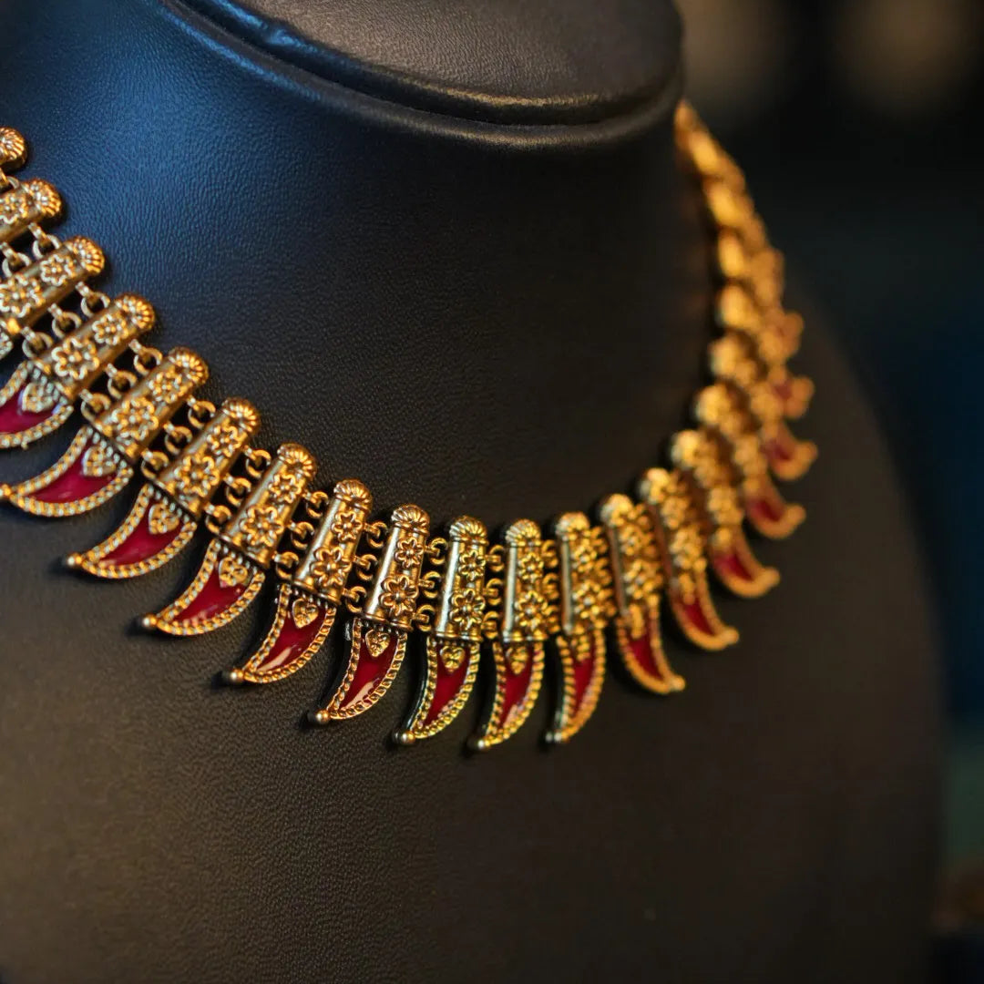 Gold and red necklace on a black mannequin bust