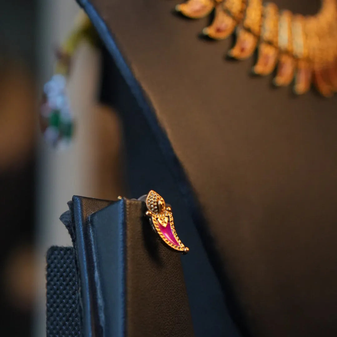 Black leather wallet with a decorative gold and red pin on a stand