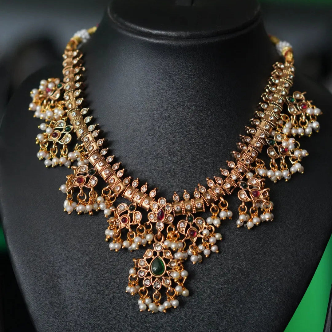 Ornate necklace on a black mannequin with a blurred green background