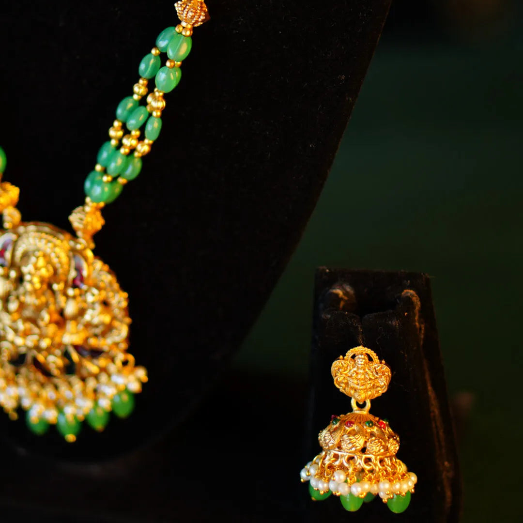 Gold and green beaded jewelry set on a dark background