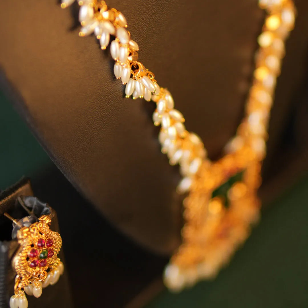 Gold necklace with pearl accents on a dark background