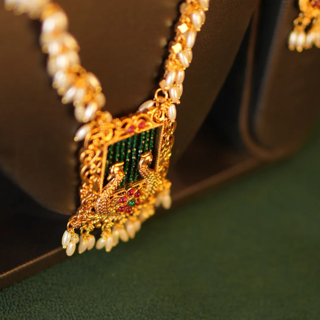 Gold necklace with a green gemstone pendant on a brown surface