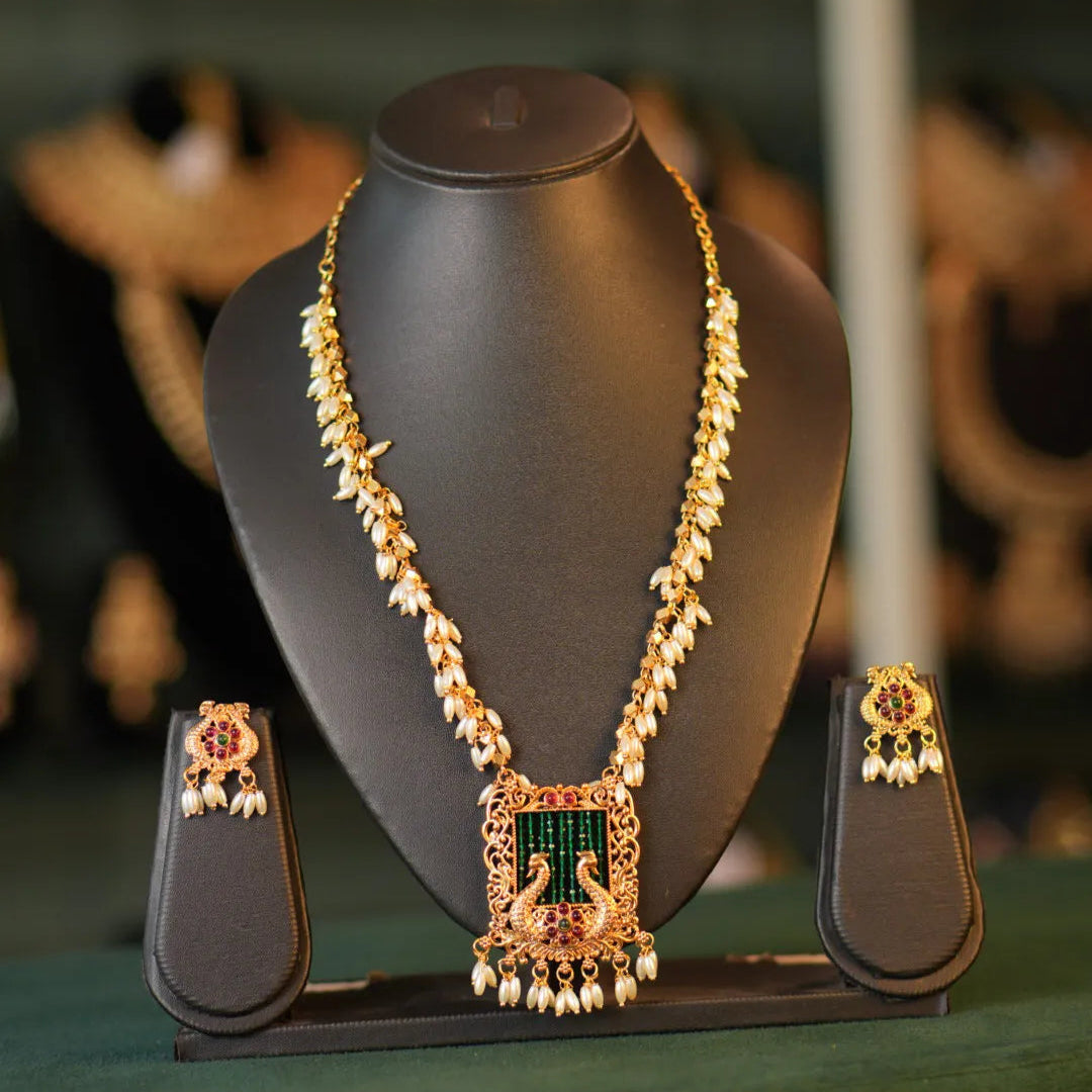 Jewelry set with necklace and earrings on a black stand against a blurred background