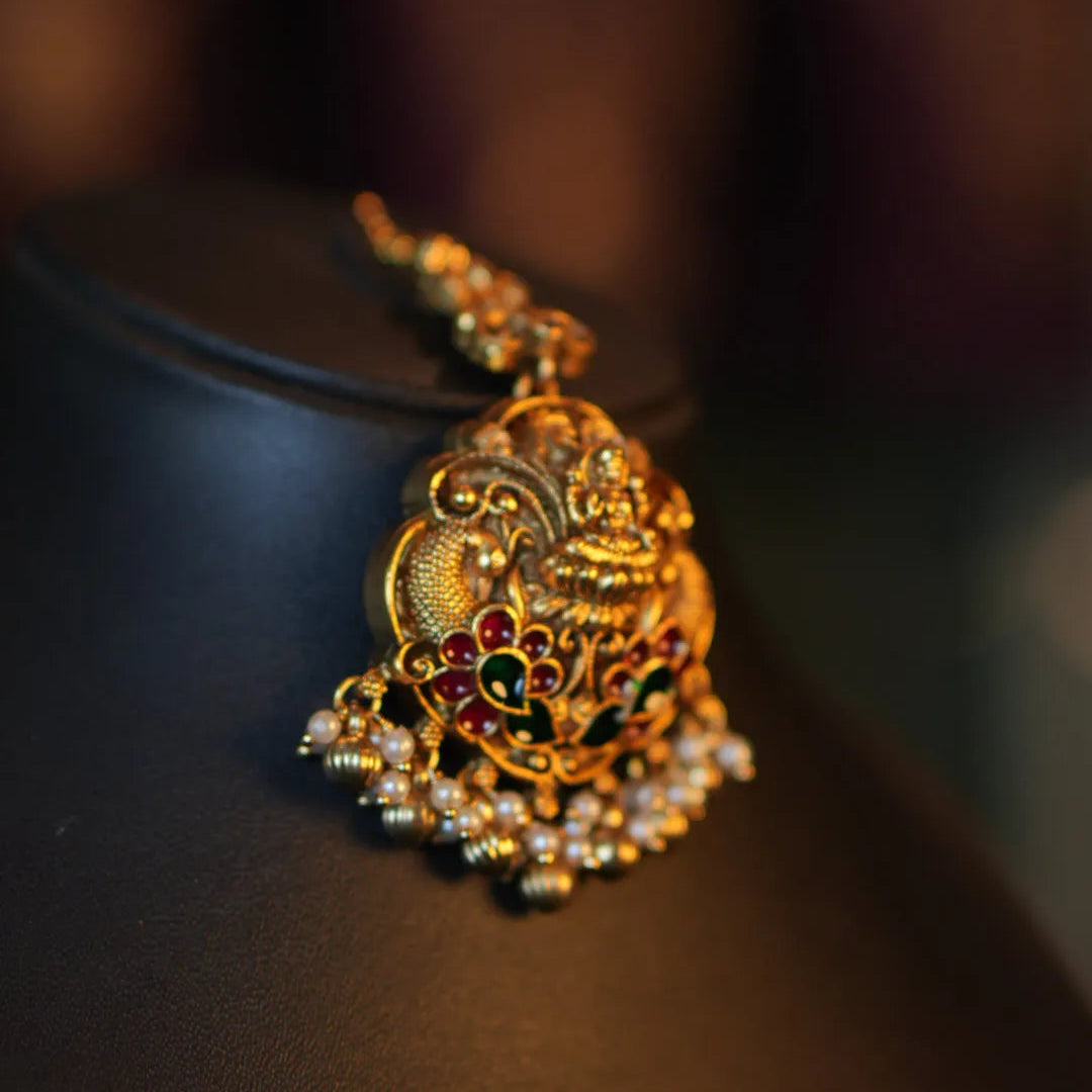 Gold necklace with intricate design on a dark background