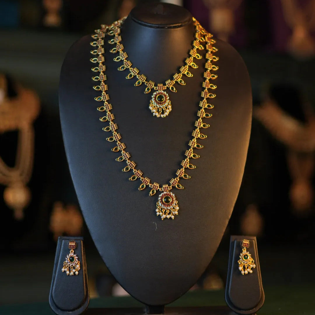 Gold necklace and earrings on a black mannequin bust with a blurred background