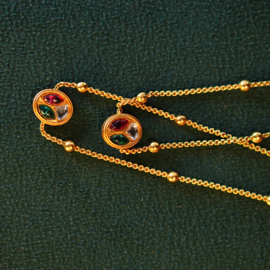 Gold necklace with colorful gemstones on a green textured background