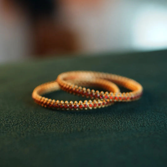 Two orange bracelets on a green surface with a blurred background