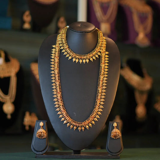 Gold necklace and earrings on a mannequin bust with a blurred jewelry store background.