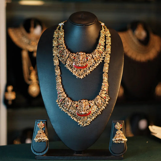 Ornate necklace and earrings on a mannequin bust with a blurred jewelry store background.