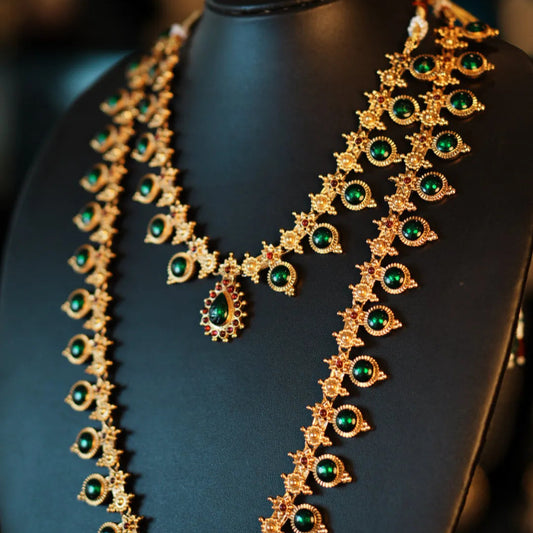 Gold necklace with green gemstones on a black mannequin