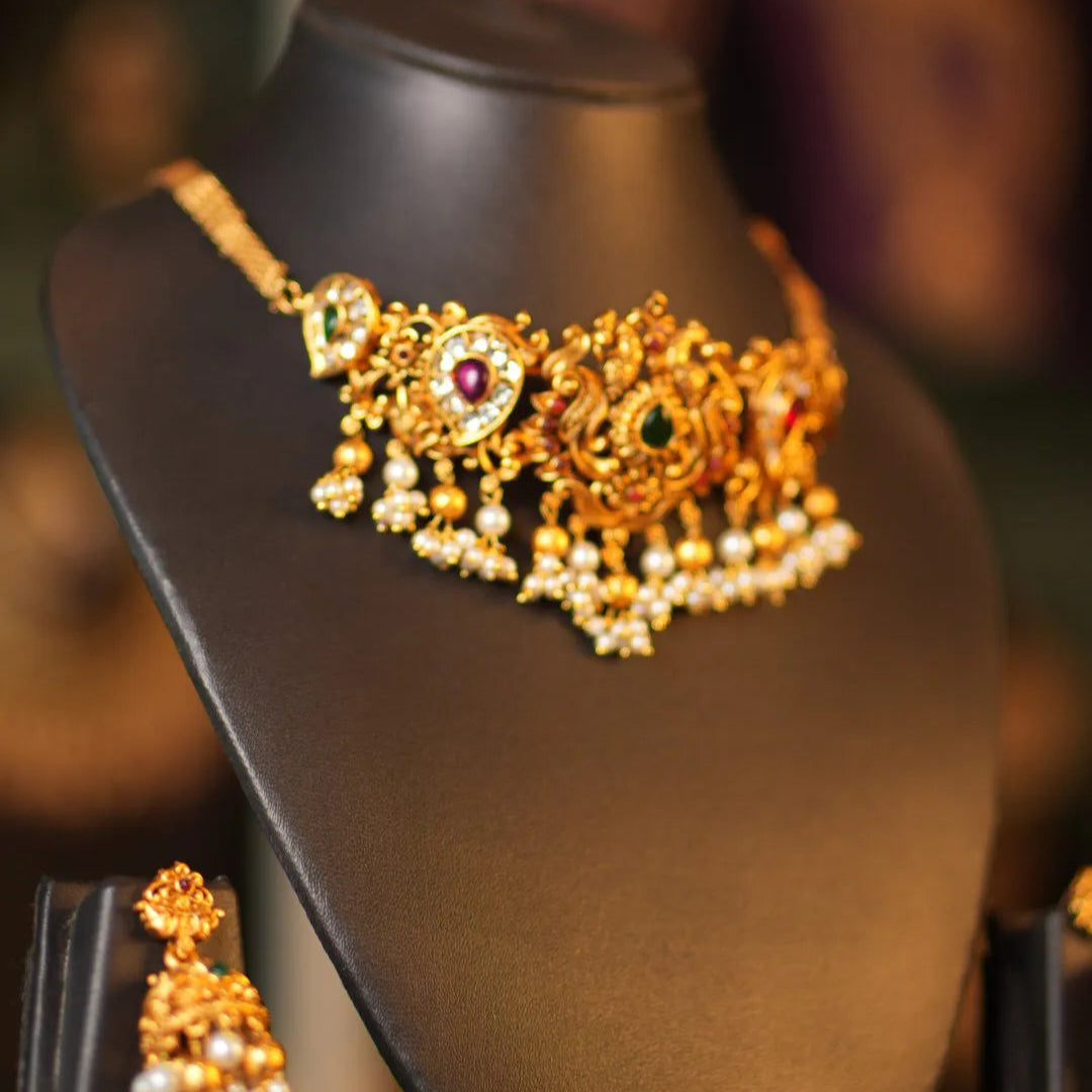 Gold necklace with a red gemstone on a mannequin bust against a blurred background