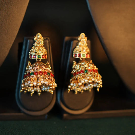 Pair of ornate gold earrings with gemstones on a dark background