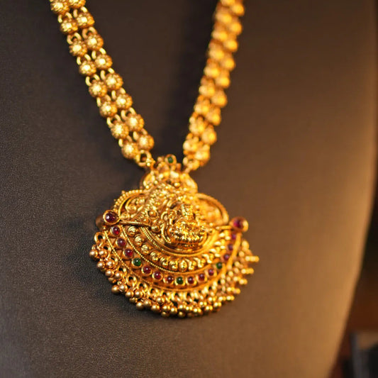 Gold necklace with a detailed pendant on a dark background