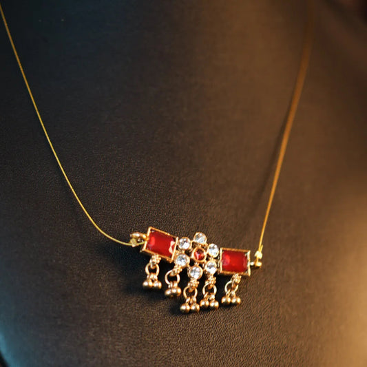 Necklace with a red and gold pendant on a dark background